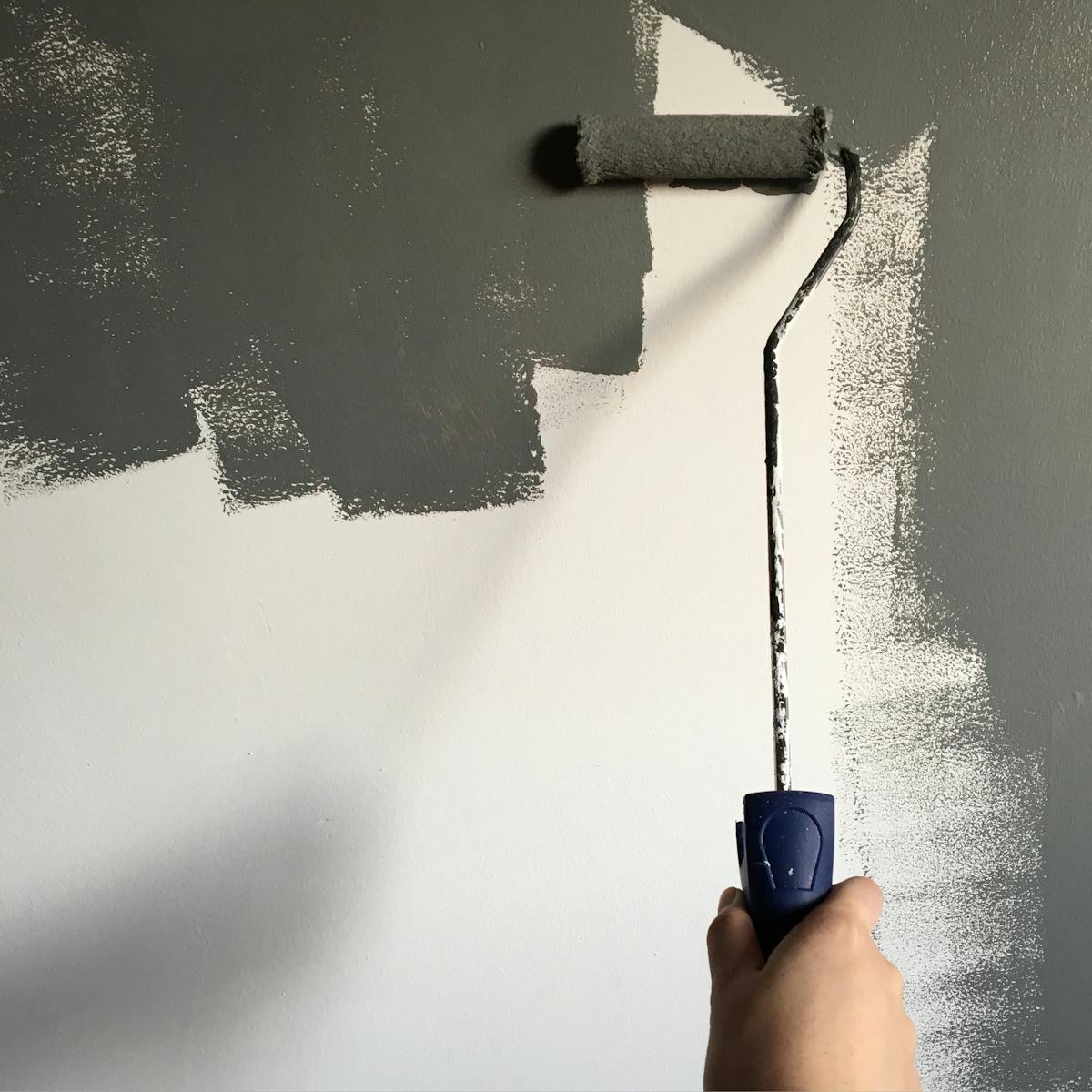 Person painting a wall with a roller